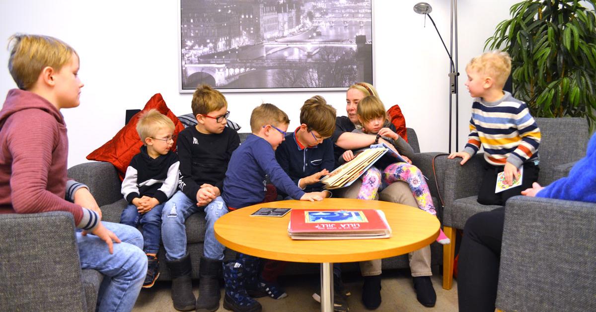 Barn i åldern 5-12 år sitter på soffa och läser taktil bok med Tessa Bamberg.
