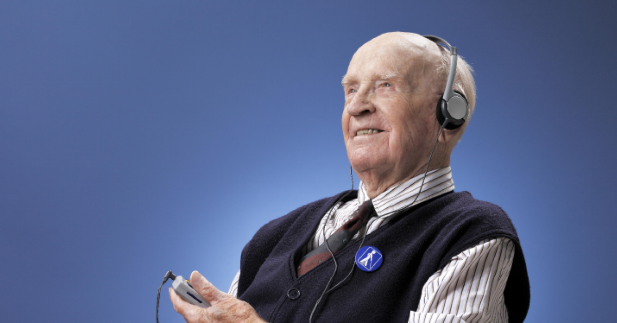 Äldre man som har hörlurar och lyssnar glatt och intresserat