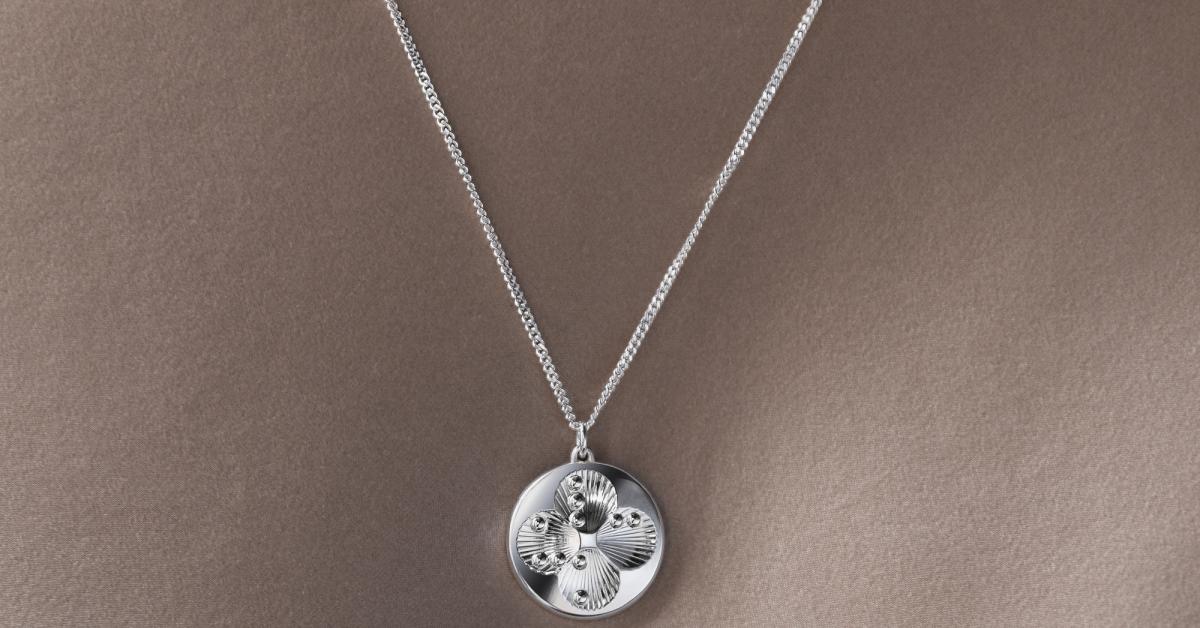 Lucky Dots är ett runt hängsmycke i silver med fyra nedsänkta rundlar på den linsformade framsidan. De symboliserar fyrklöverns blad och är var för sig märkta med punktskriftsbokstäverna L, U, C och K. Rundlarnas bottnar är dekorerade med tunna linjer som påminner om snäckmönster, och kompositionen av de fyra rundlarna bildar en stiliserad stjärna i mitten. Smycket har en tunn, låg profil och hänger i en elegant, unisex pansarkedja.  I denna bild hänger smycket runt halsen