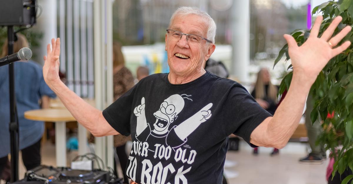 En skrattande äldre man med t-tröja med texten "Never too old to rock".