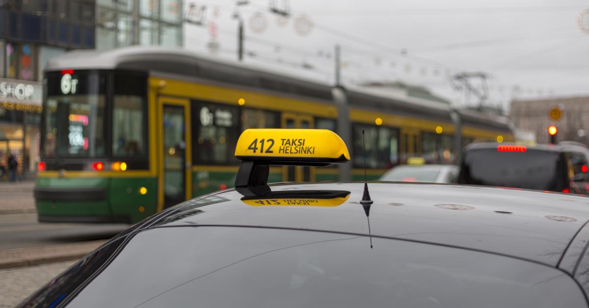 Taxi i närbild, spårvagn i bakgrunden.